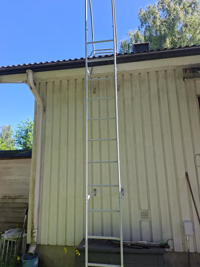 Seinätikkaat asennettuna talon päätyyn, yläpäässä kaide ja siirtyminen lappeelle